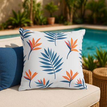 Decorative pillow with tropical leaf pattern on a patio with pool and plants in the background